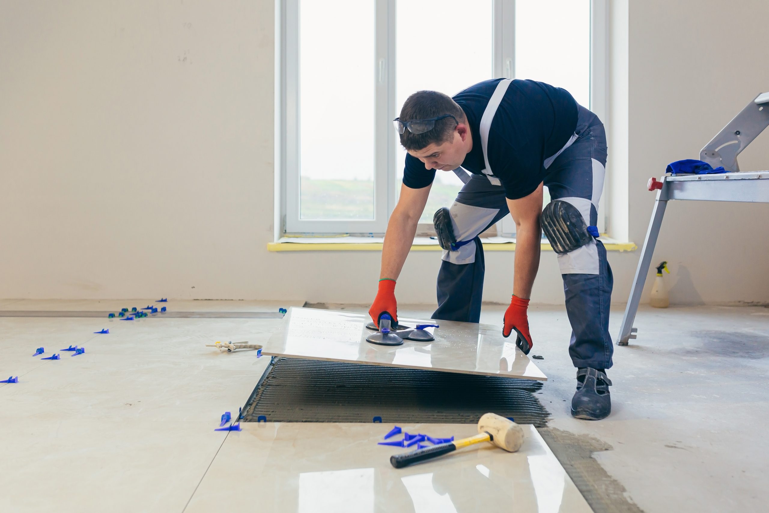 A Male Construction Worker Installs A Large Ceramic Tile — Pro Chicago Painters